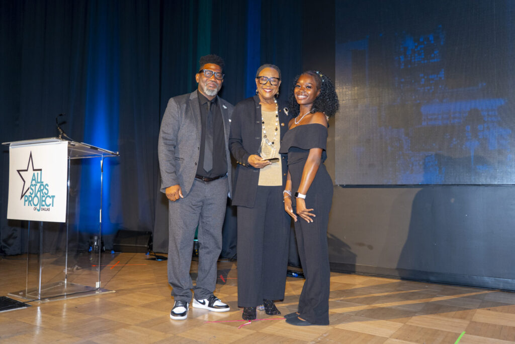 Cynt on stage posing with two people