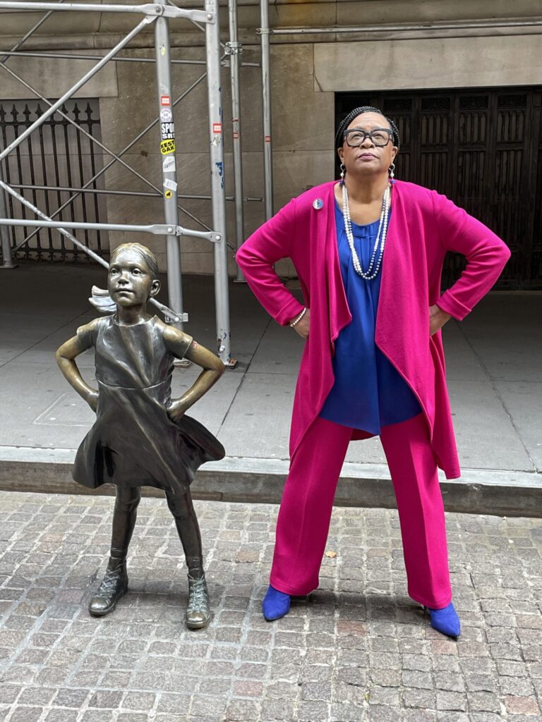 Cynt posing with statue in front of Wall Street